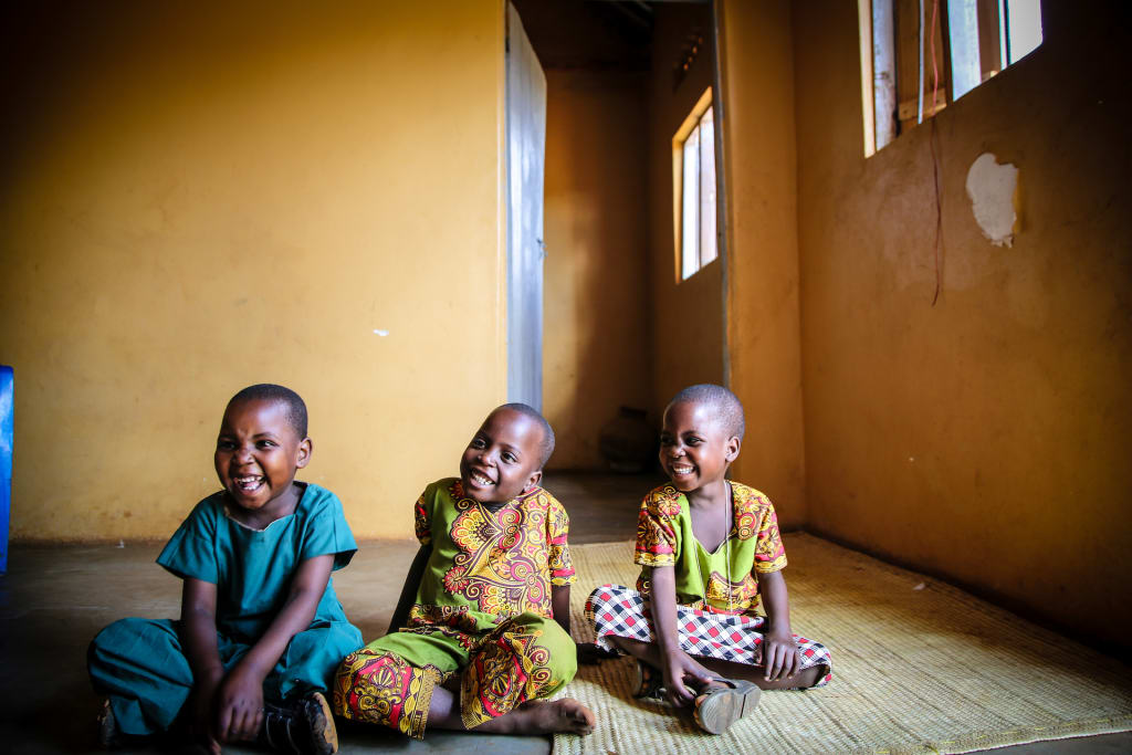 Triplets laugh and smile at the camera in their home